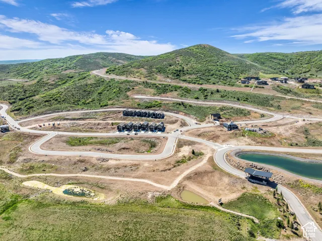Multiple residential structures, paved roadways, and natural green landscaping with water features