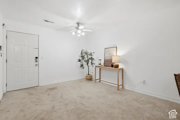 Neutral wall paint, ceiling fan with integrated lighting, door with paneling, baseboard trim, and carpeted flooring