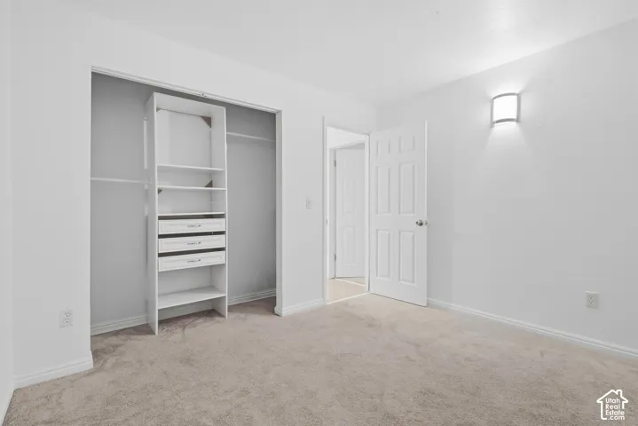 Neutral-toned carpet flooring, white walls, and a wall-mounted sconce