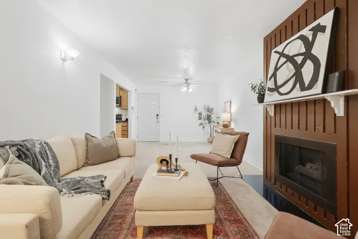 Living room with a fireplace featuring vertical wood paneling and a white mantel
