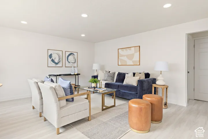 Recessed lighting, light wood-finish flooring, white walls, and a white interior door