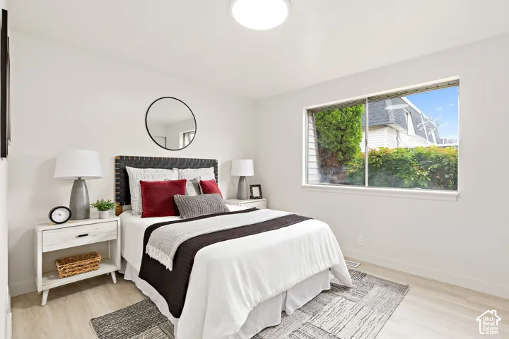 Light-colored wood-finish flooring, white walls, and a large window with exterior landscaping