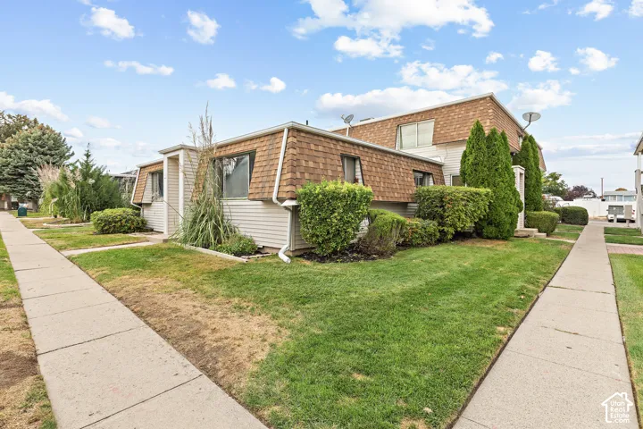 Two-story structure with shingled mansard roofs, white siding, and concrete walkways