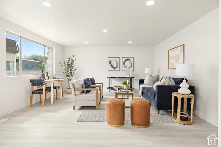 Recessed ceiling lighting, wood-finish flooring, white painted walls, large multi-pane window, and a built-in window sill