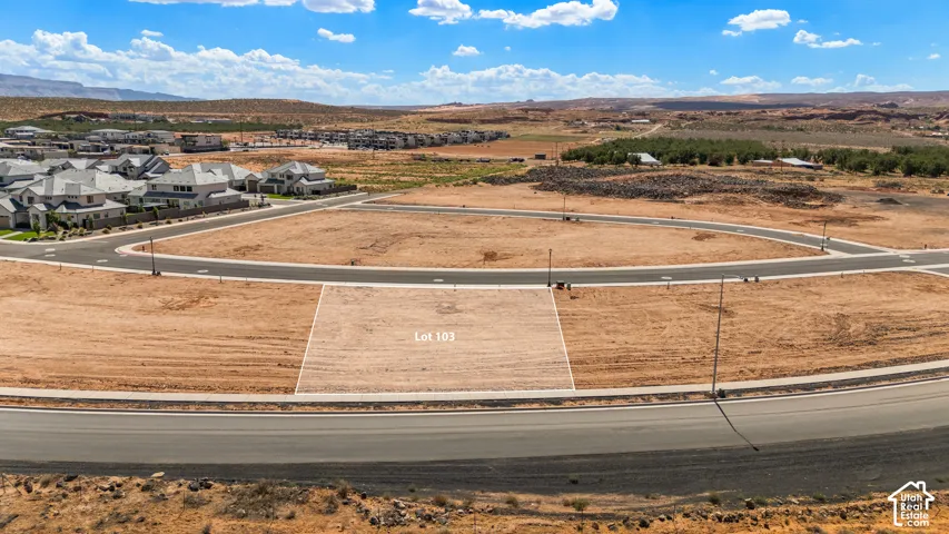 Gradesite lot with paved road frontage, surrounding residential development, and expansive desert landscape