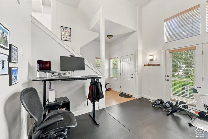 Two-story ceiling, abundant natural light, transom window, white paneled door, and wood-finish flooring