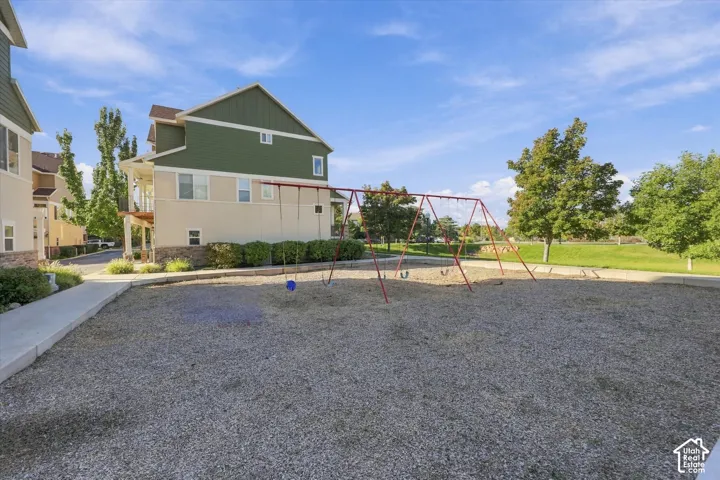 Expansive common area featuring a swing set, gravel ground cover, and surrounding green space
