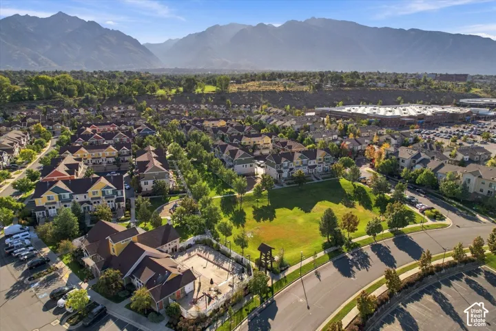 Expansive community with mountain backdrop, residential buildings, recreational green space, and nearby commercial development