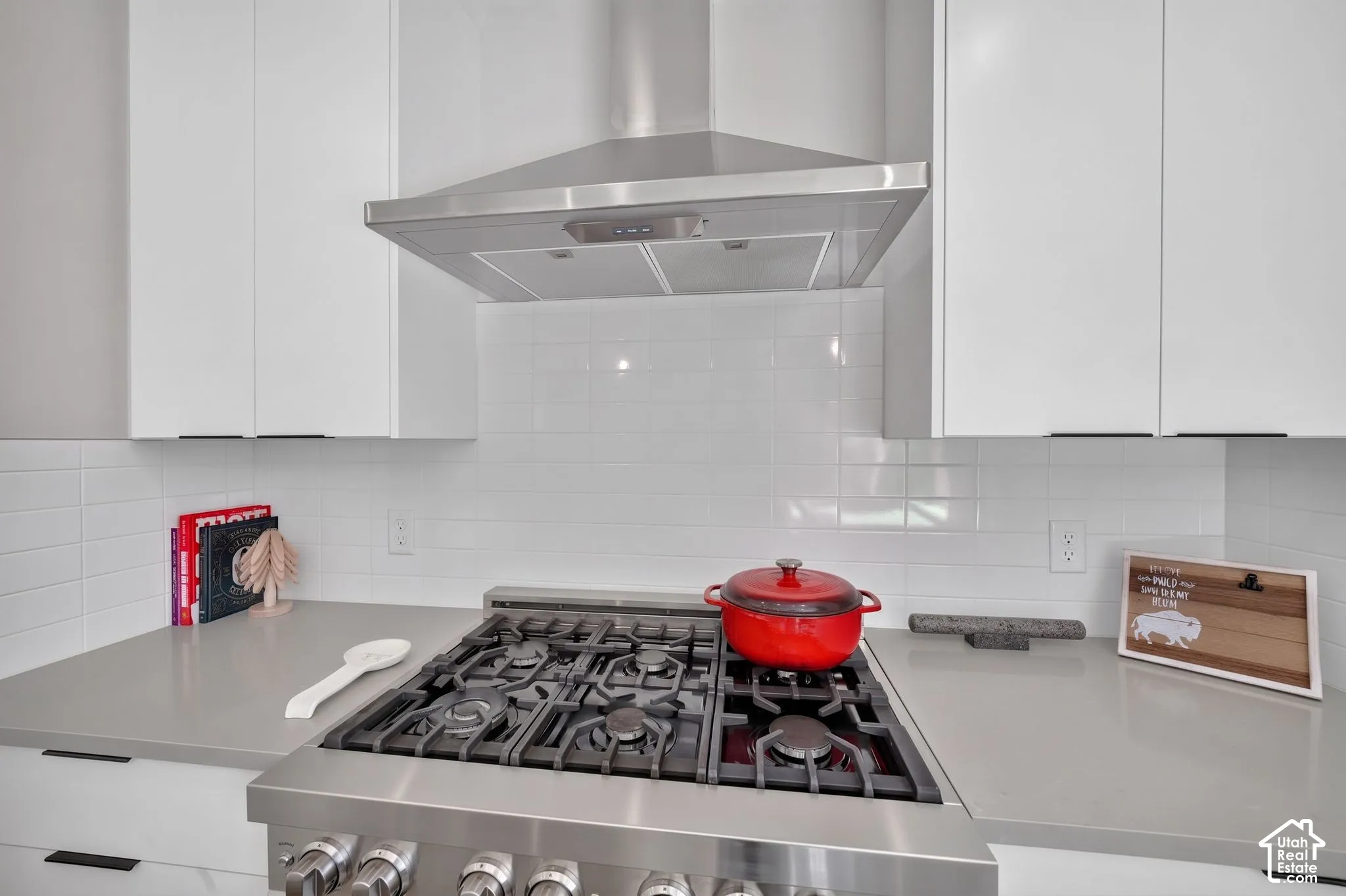 Stainless steel gas range with a coordinating range hood and white subway tile backsplash