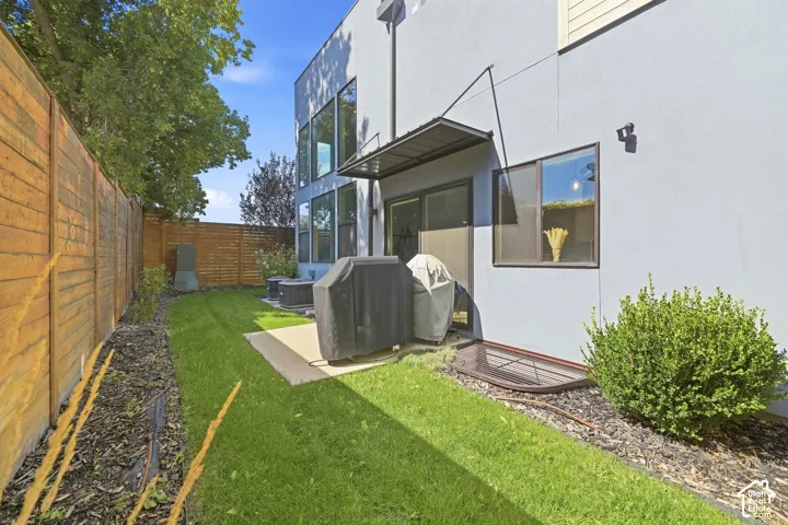 Private backyard with a wood fence, concrete patio, and mature landscaping