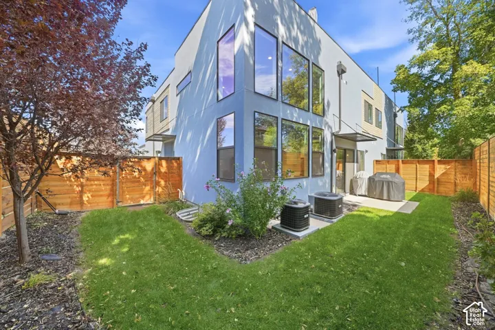 Private outdoor space with manicured lawn, concrete patio, and slatted wood fencing