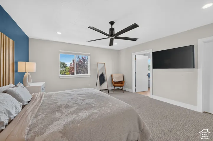 Recessed lighting, ceiling fan with black finish, light gray carpeting, window with outdoor scenery, and a blue accent wall with wood paneling