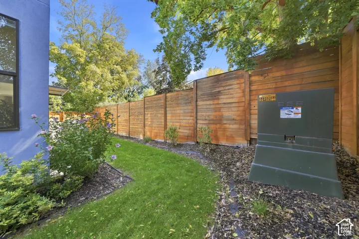 Manicured lawn with a wooden privacy fence, mature trees, and established shrubbery
