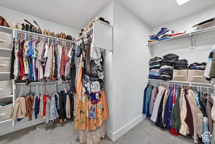 Master suite walk-in closet with built-in organization system featuring white shelving and multiple hanging rods