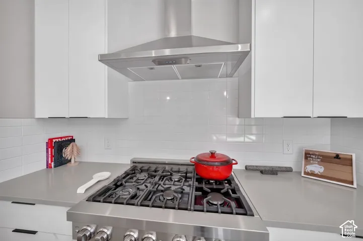 Stainless steel gas range with a coordinating range hood and white subway tile backsplash