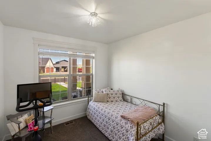 Neutral wall paint, plush carpet, window with horizontal blinds, and a built-in ceiling light fixture