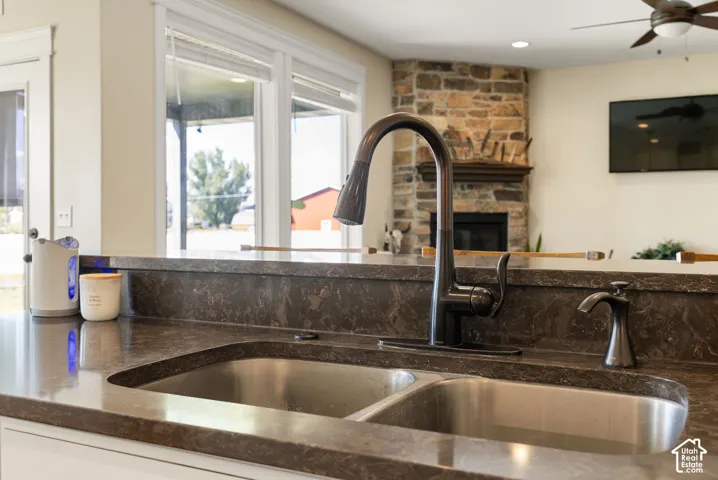 Dual-basin stainless steel sink with a dark bronze faucet and integrated soap dispenser, set into a dark-toned countertop