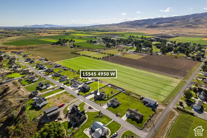Expansive aerial perspective showcasing a residential neighborhood with surrounding agricultural fields and distant mountainous terrain