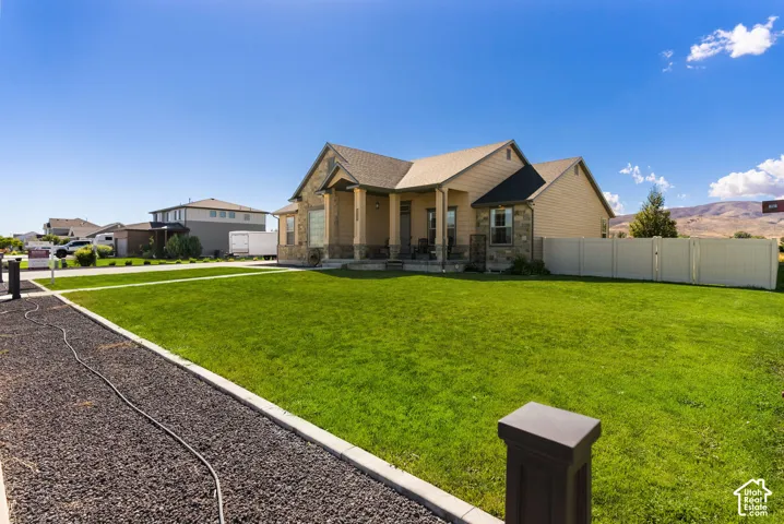 Expansive front lawn with a decorative stone pathway and a partial privacy fence
