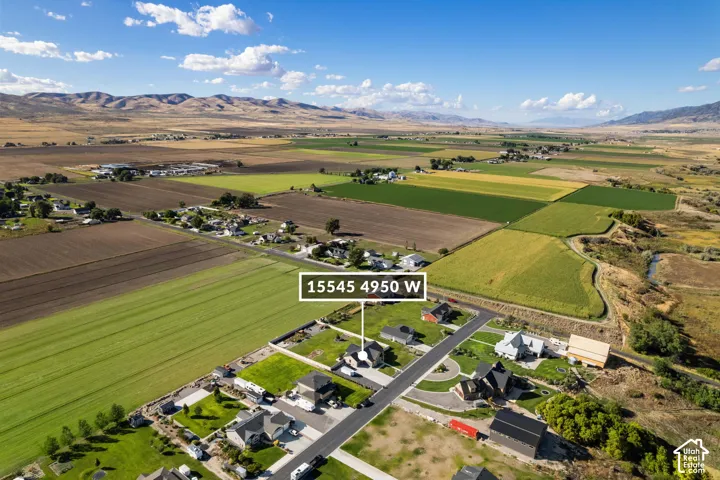 Expansive rural setting with agricultural fields, mountain backdrop, and established community