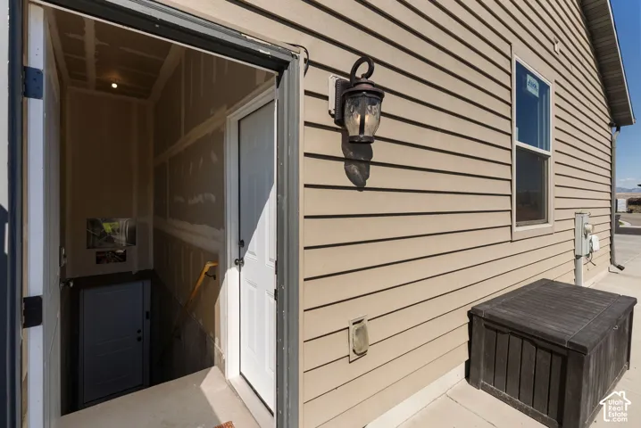 Exterior featuring horizontal siding, an outdoor wall lantern, a window, and a concrete patio