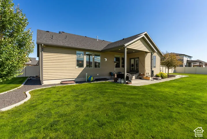 Expansive green lawn, covered patio, paved patio, gravel pathway, and mature landscaping