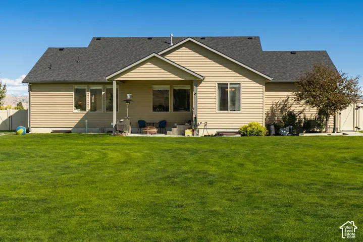 Expansive backyard with a manicured lawn, covered patio, and a mature tree