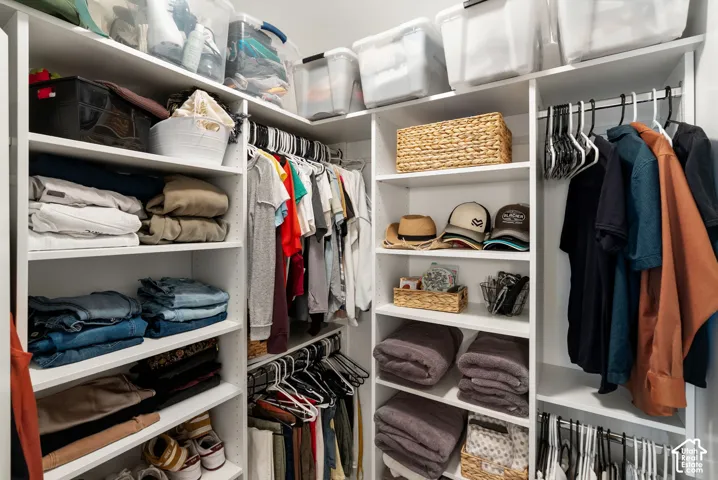 Built-in custom closet system featuring white shelving, multiple hanging rods, and ample storage compartments