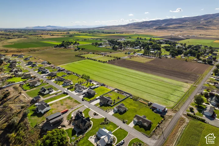 Expansive rural landscape featuring distant mountains, agricultural fields, and a residential neighborhood with paved roads
