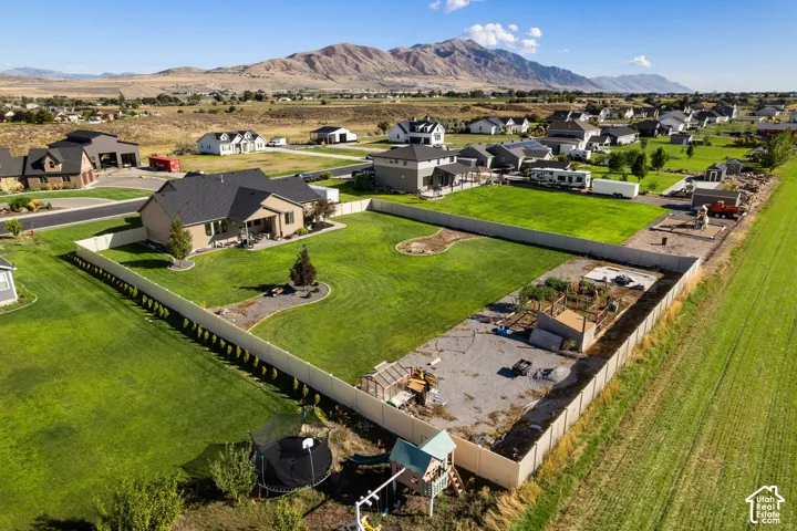 Expansive property featuring a single-story residence, a large manicured lawn, a gravel-covered area, and a privacy fence