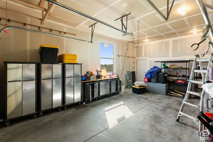 Concrete flooring, window for natural light, interior access door, track lighting, and exposed ceiling joists