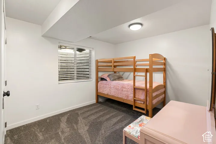 White painted walls and trim, textured carpet flooring, and a recessed window with horizontal blinds