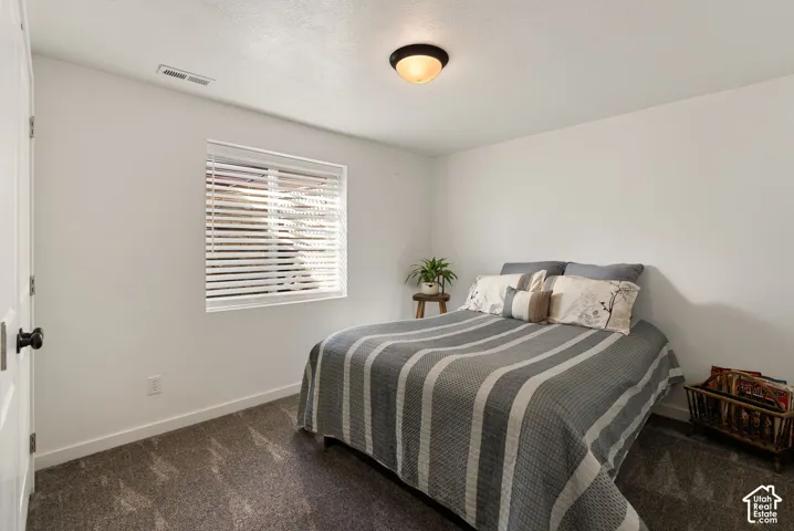 White walls with textured ceilings, featuring a window with horizontal blinds and recessed window casing, and carpet flooring