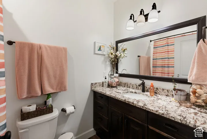 Granite-style countertop with an undermount sink, dark wood-finish vanity, and a large framed mirror with overhead lighting