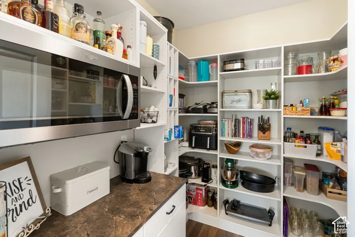 Built-in white shelving, stainless steel microwave, and dark countertop