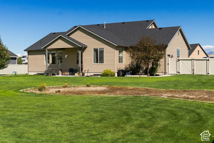 Expansive rear yard with manicured lawn, covered patio, and privacy fencing