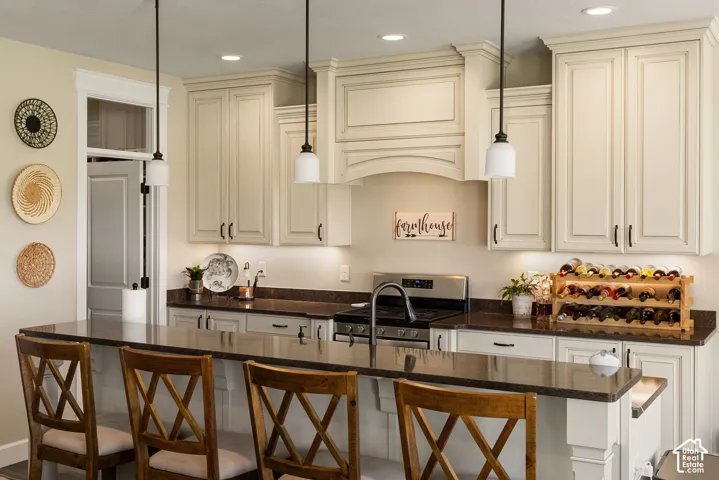 Kitchen featuring cream-colored cabinetry, recessed lighting, pendant lighting, and dark countertops
