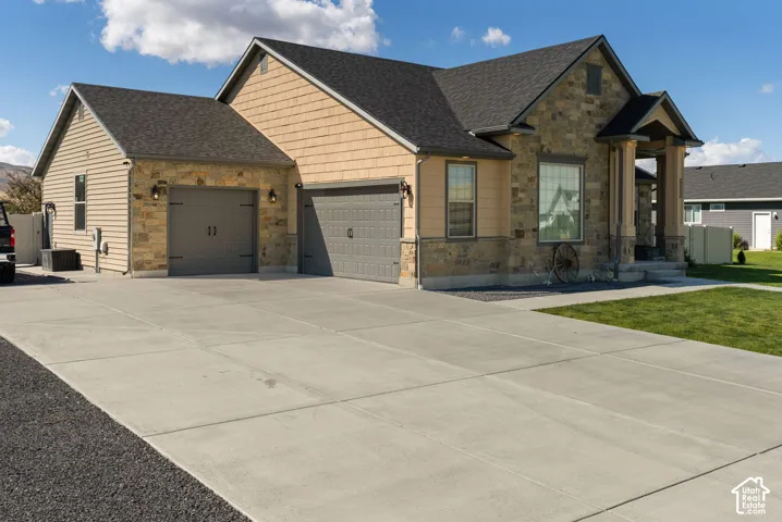 Stone and siding exterior with a covered entry, concrete driveway, and attached two-car garage