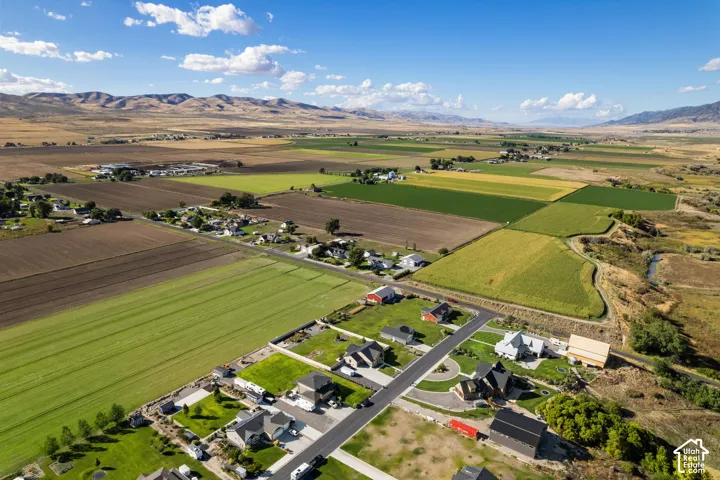 Expansive rural landscape featuring a river, cultivated fields, and distant mountains