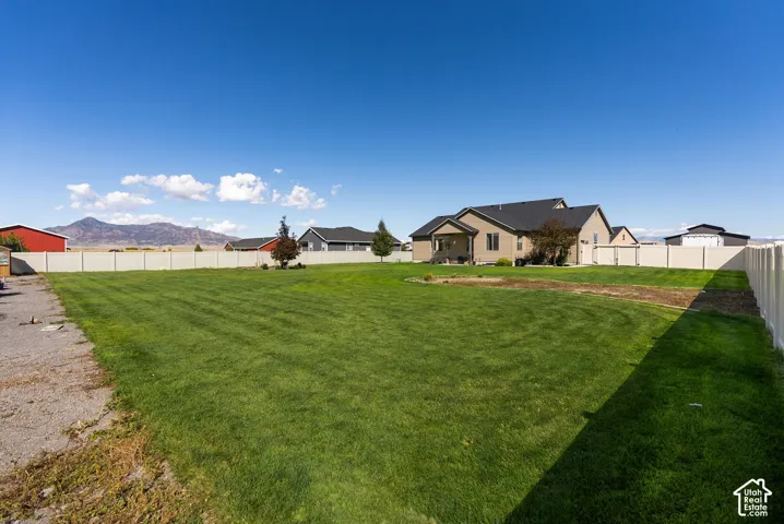 Expansive backyard featuring a manicured lawn, full fencing, and a covered patio