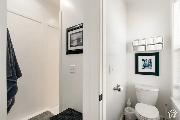 Modern bathroom featuring a spacious walk-in shower with glass enclosure and tile surround, white subway tile walls, a porcelain toilet, and a window providing natural light