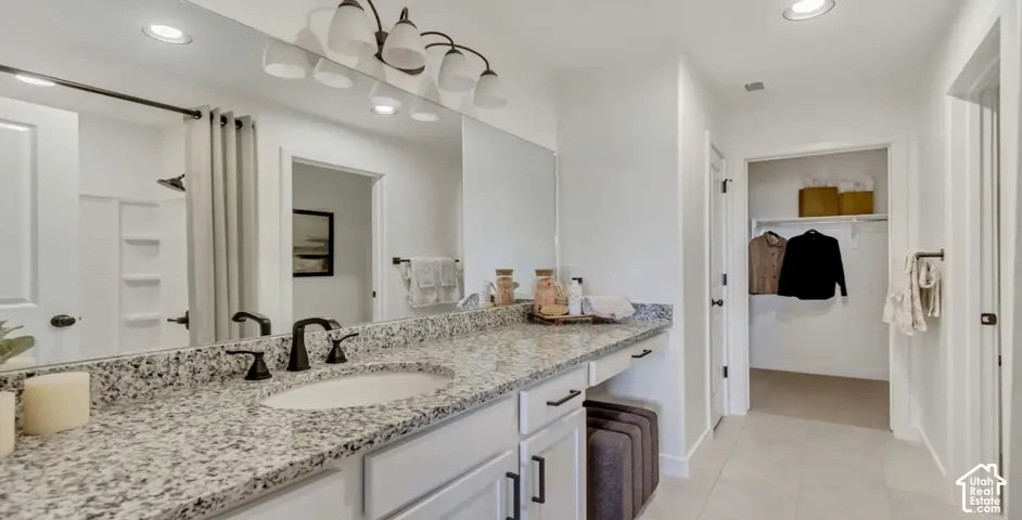 Bathroom featuring dual vanity with stone countertops, integrated oval sinks, dark bronze fixtures, and an expansive wall-mounted mirrors. This home is under construction. Pictures are of a similar home