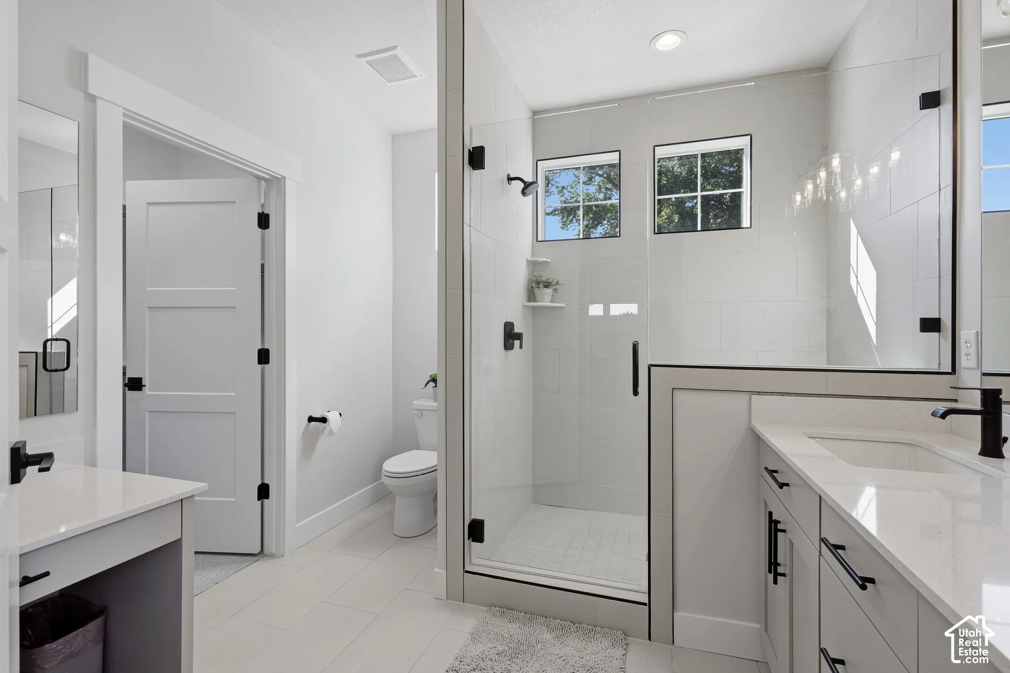 Primary bathroom with dual vanities, separate makeup counter and oversized shower with euro glass