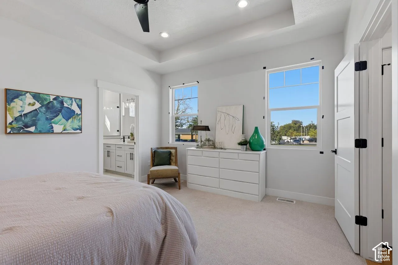 Main level primary suite with tray ceiling, ample natural light, neutral colors and attached bath