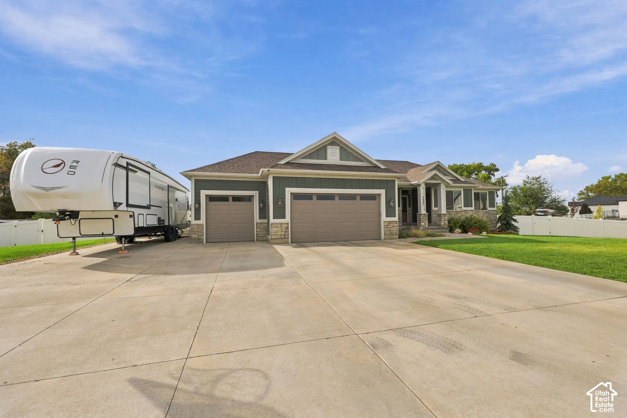 Spacious concrete driveway, stone and siding exterior, two-car garage, front entry with covered porch, and a fenced yard