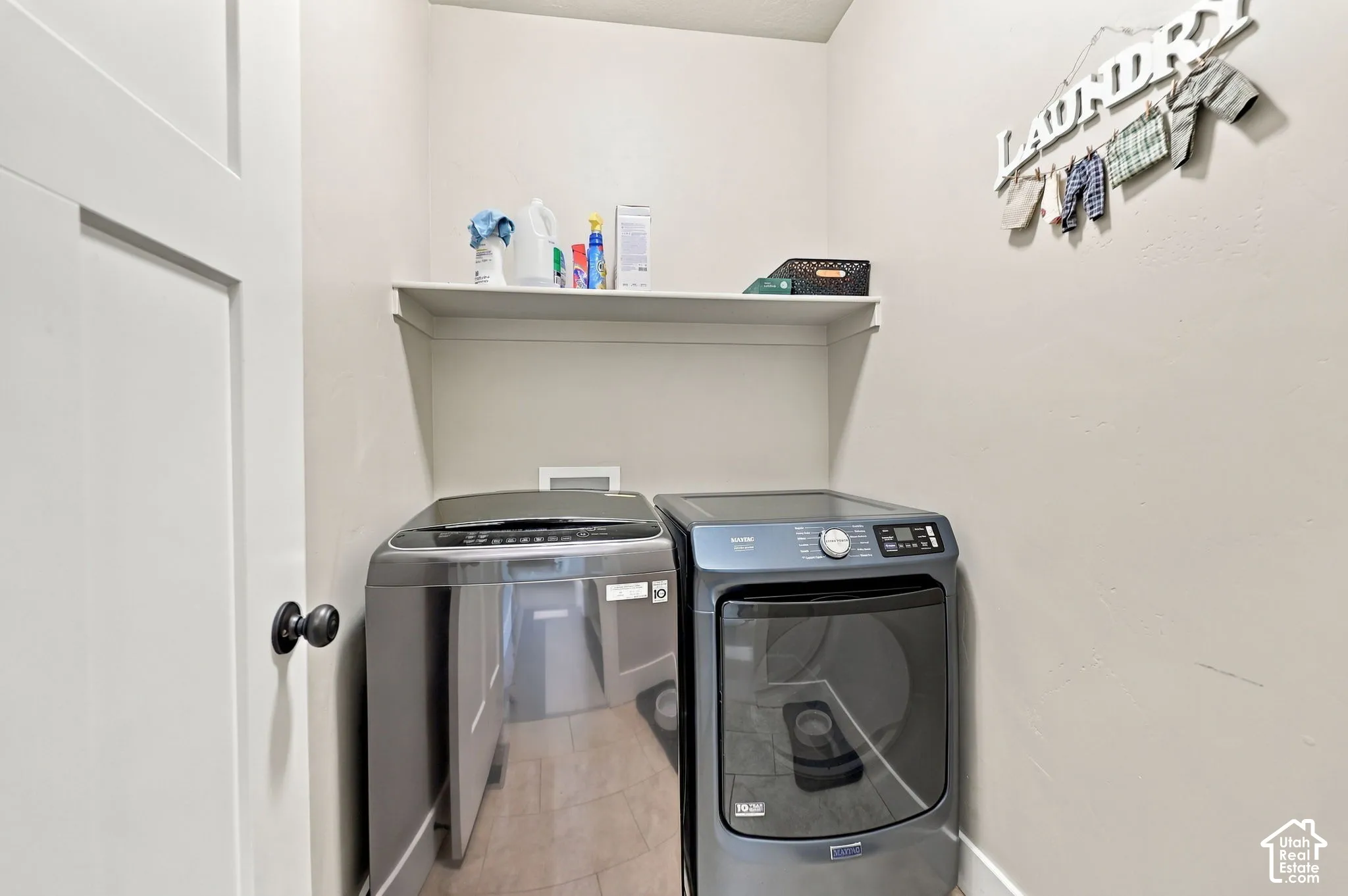 Dedicated laundry space with a built-in shelving unit and light-toned walls