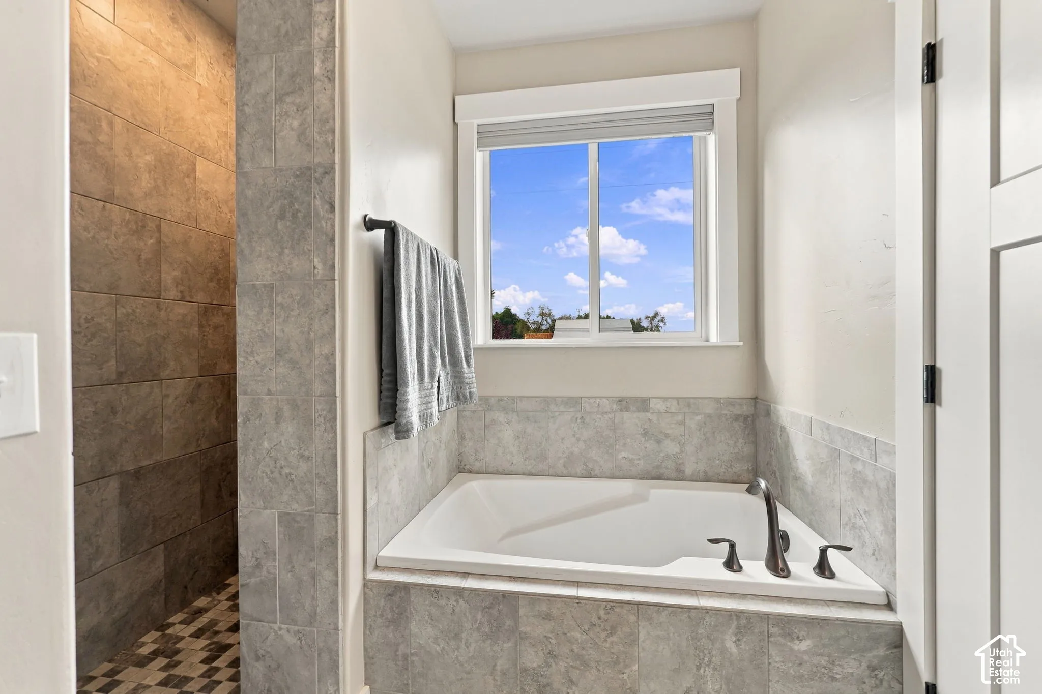 Built-in soaking tub with a bronze-finish faucet, tile surround, and a clear window