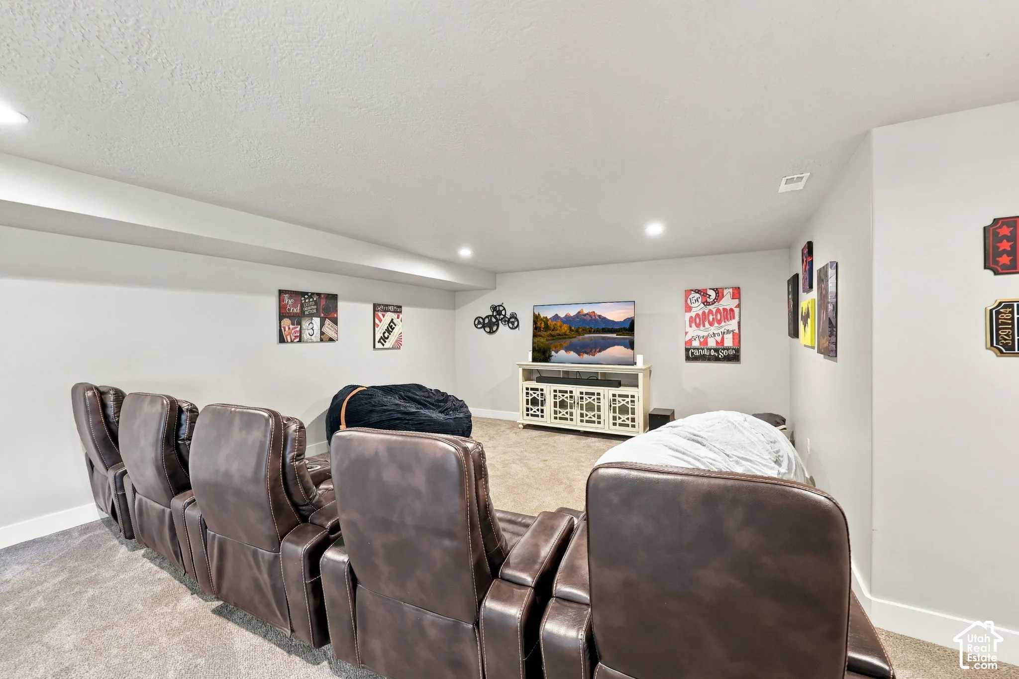 Spacious entertainment area with recessed lighting, light gray walls, and carpet flooring