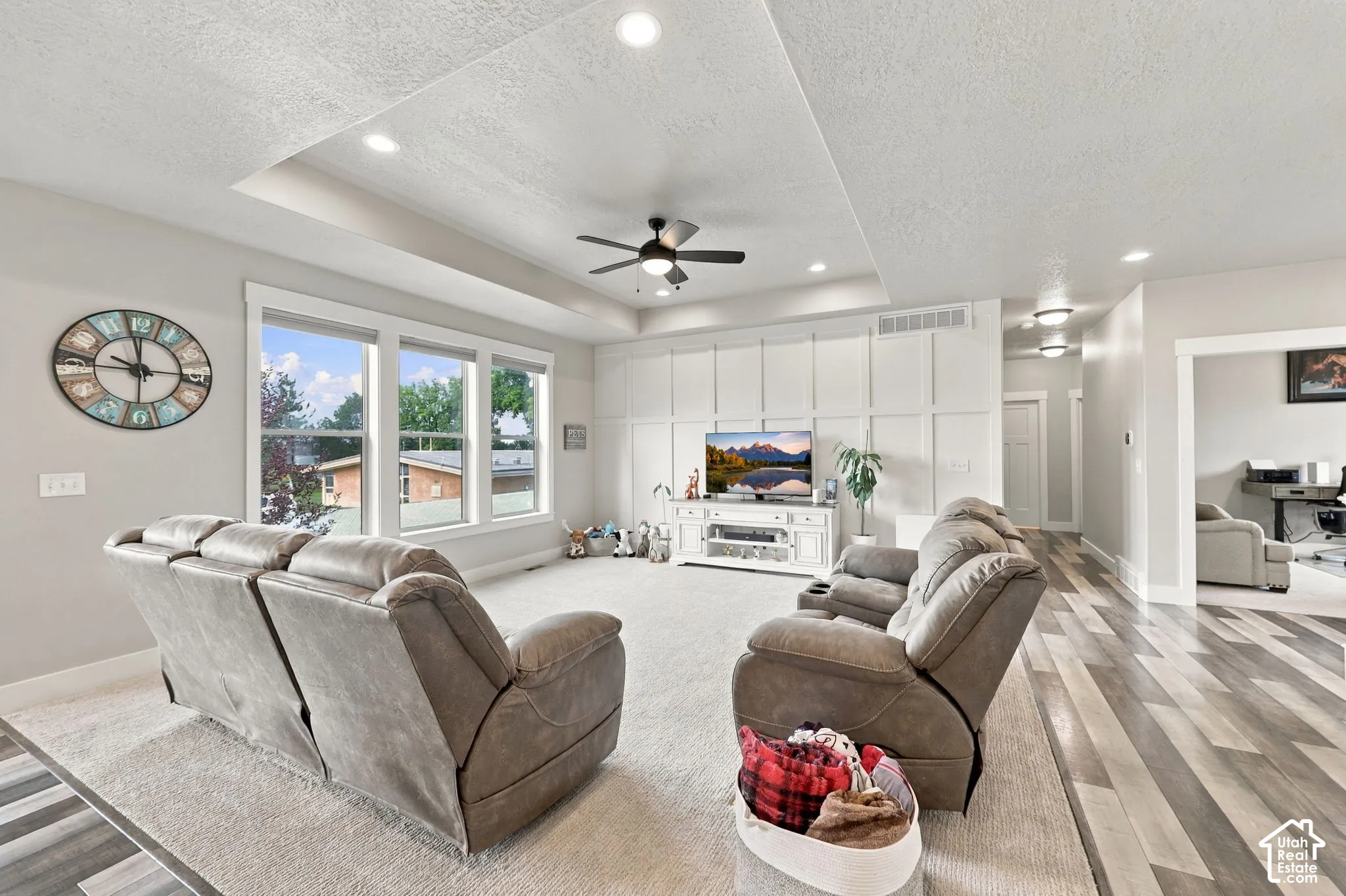 Recessed lighting, tray ceiling, ceiling fan, board and batten accent wall, wood-finish flooring