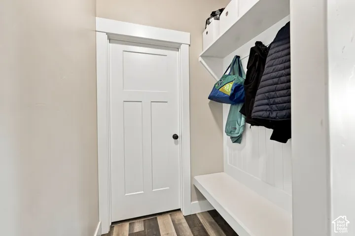 Entryway featuring a built-in bench, overhead shelving, wall-mounted coat hooks, and wood-finish flooring